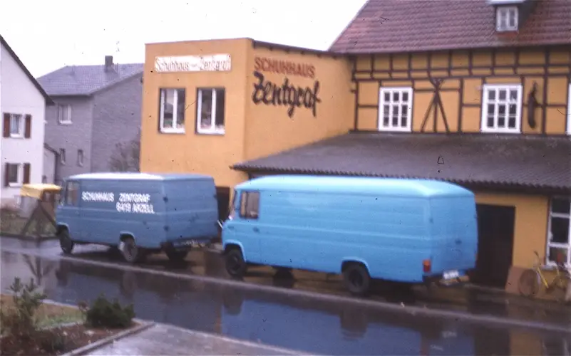 Schuhhaus Zenthof Fachwerkhaus mit zwei blauen Lieferwagen auf nasser Straße