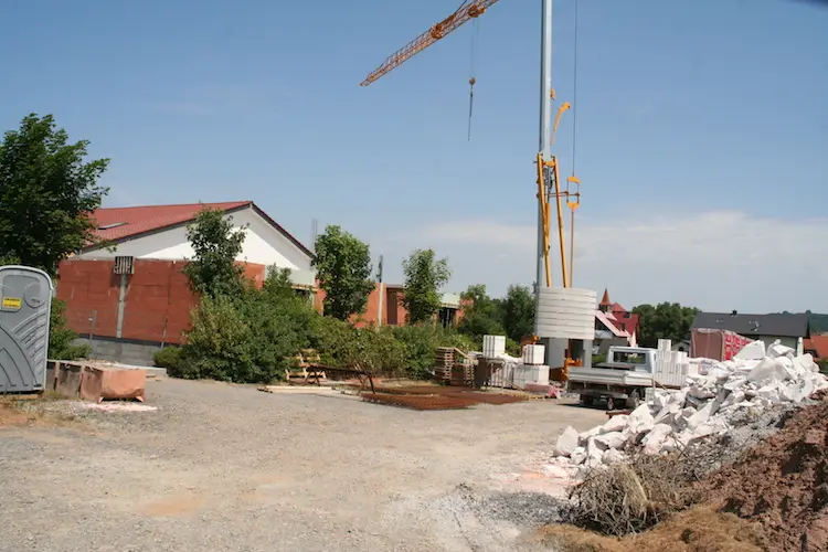 Baustelle mit Turmdrehkran, Baumaterialien, Schuttberg und halbfertigen Wohnhäusern