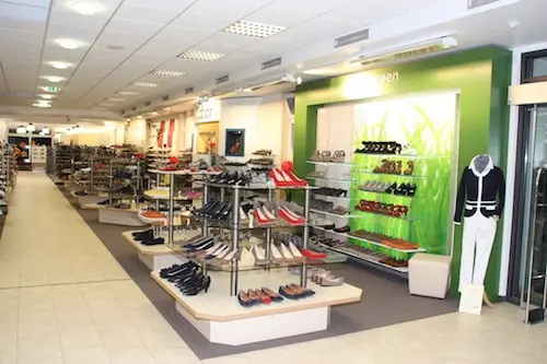 Innenansicht eines modernen Schuhgeschäfts mit Regalen und zahlreichen Damen- und Herrenschuhen